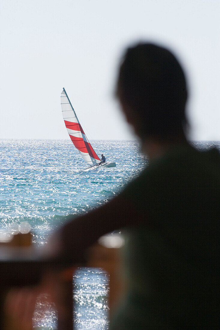 Person beobachtet Segelboot auf dem Meer, Apulien, Italien