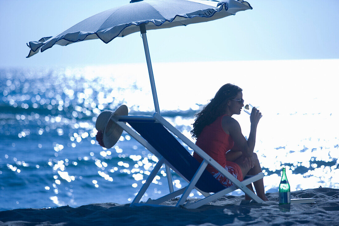 Junge Frau im Liegestuhl am Strand, Apulien, Italien