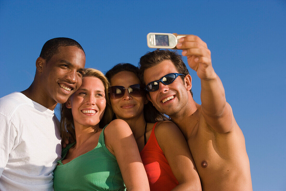 Four young people taking picture with camera phone, Apulia, Italy