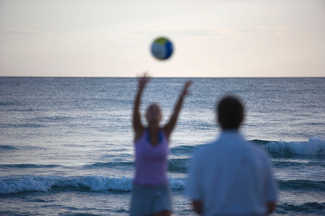 Two people playing with ball on beach, Apulia, Italy
