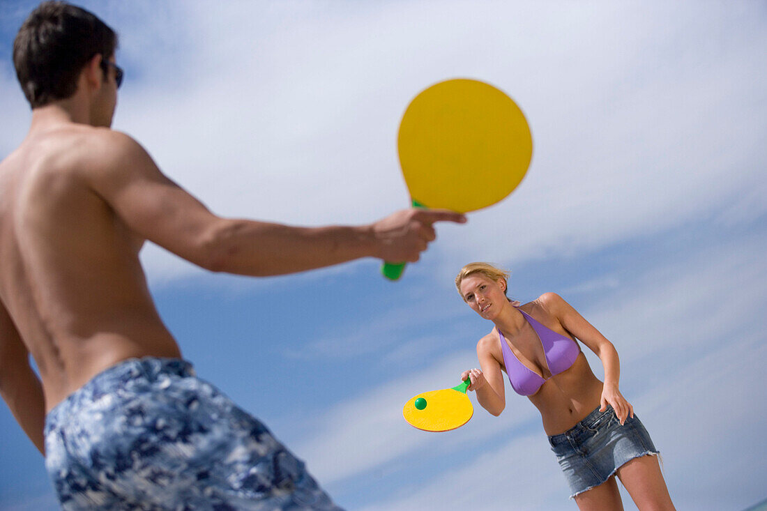 Young couple playing paddle ball on beach, Apulia, Italy