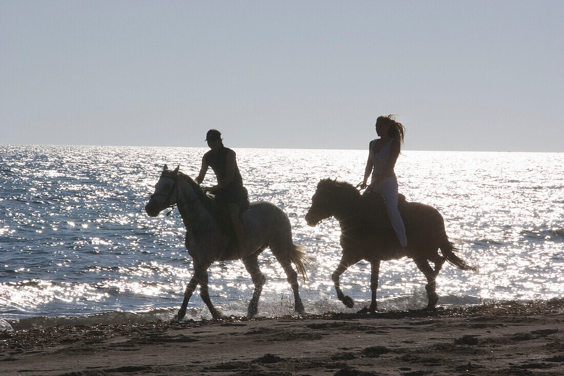 Junges Paar reitet am Strand, Apulien, Italien