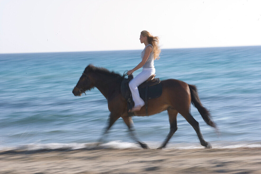 Junge Frau reitet am Strand, Apulien, Italien