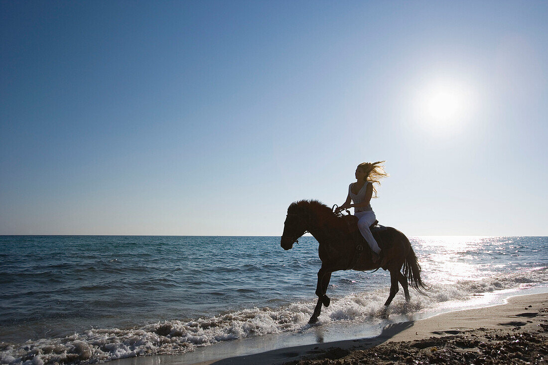 Junge Frau reitet am Strand, Apulien, Italien