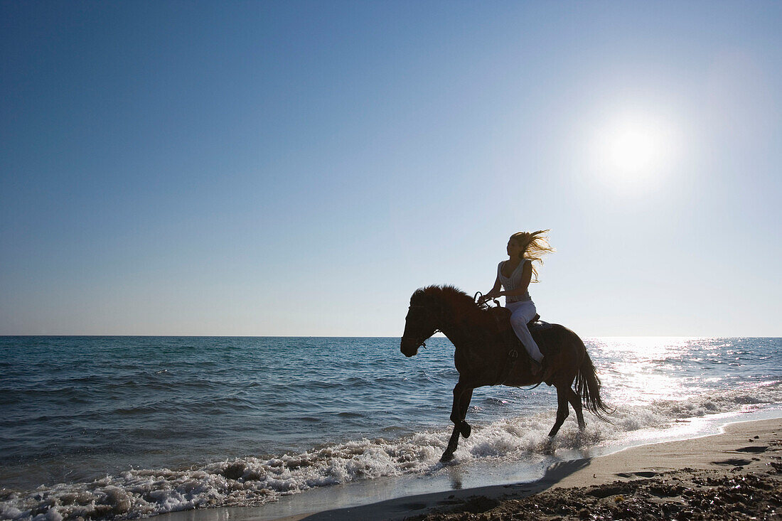 Young woman riding horse on beach, Apulia, Italy