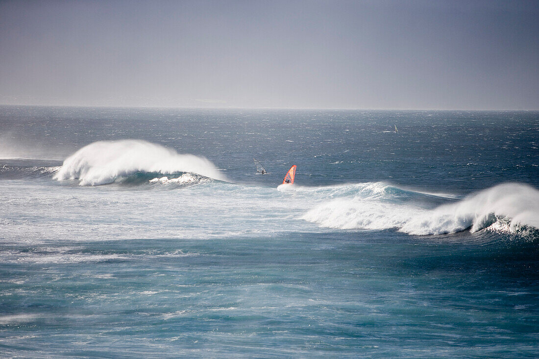 Windsurfer und Riesenwellen in der Nähe von Hookipa Beach, Maui, Hawaii, USA