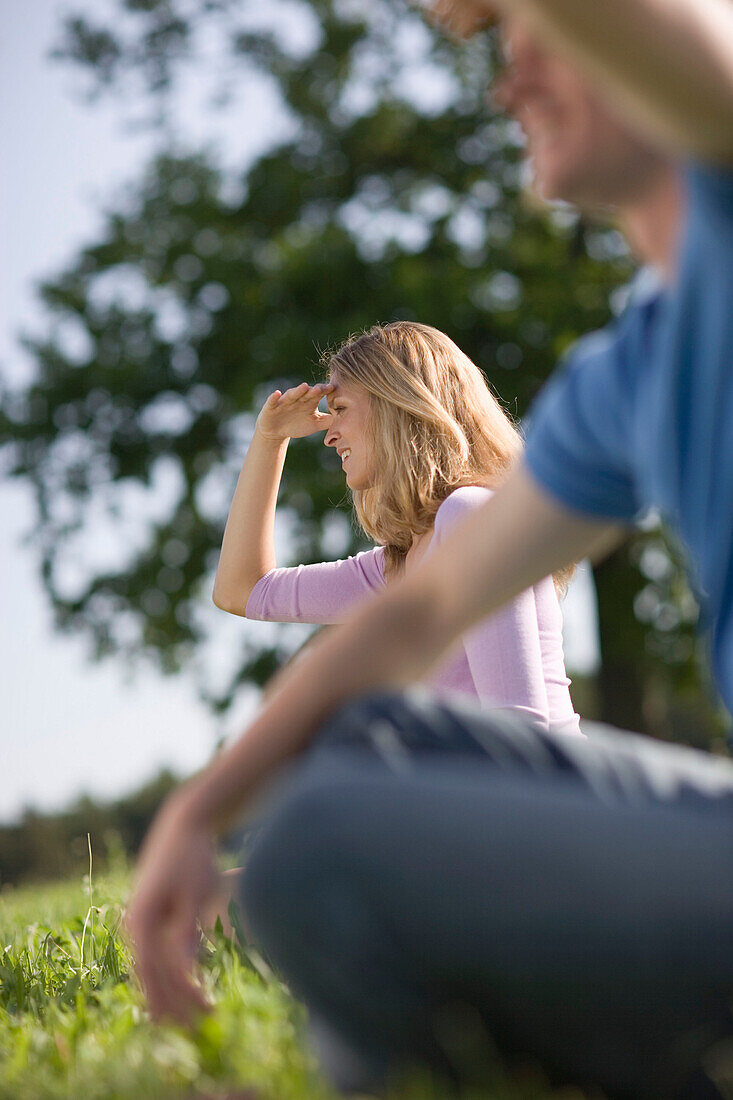 Man and woman sitting on meadow and watching out