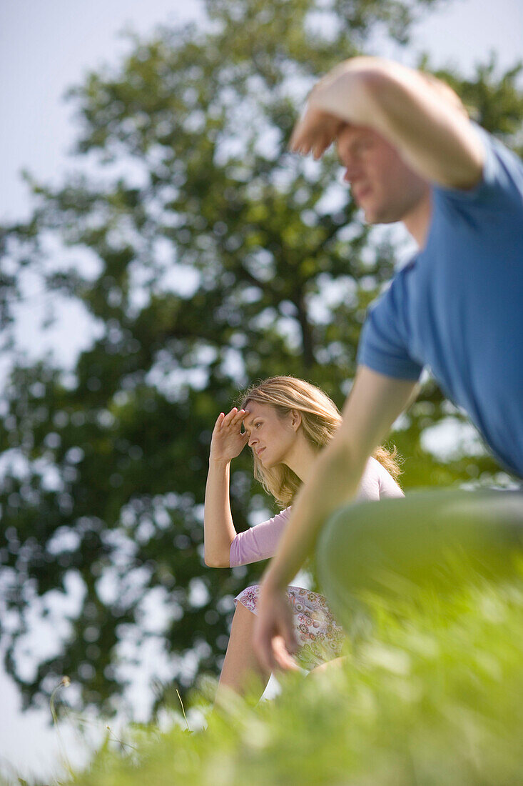 Man and woman sitting on meadow and watching out