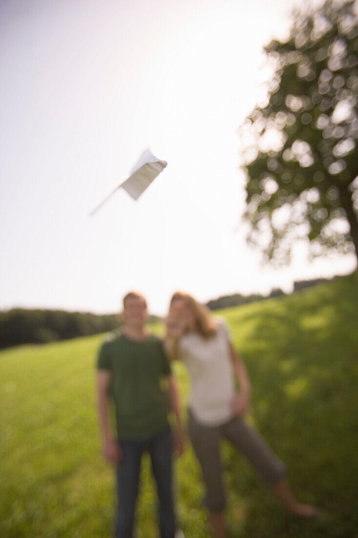 Young woman throwing paper airplane on meadow