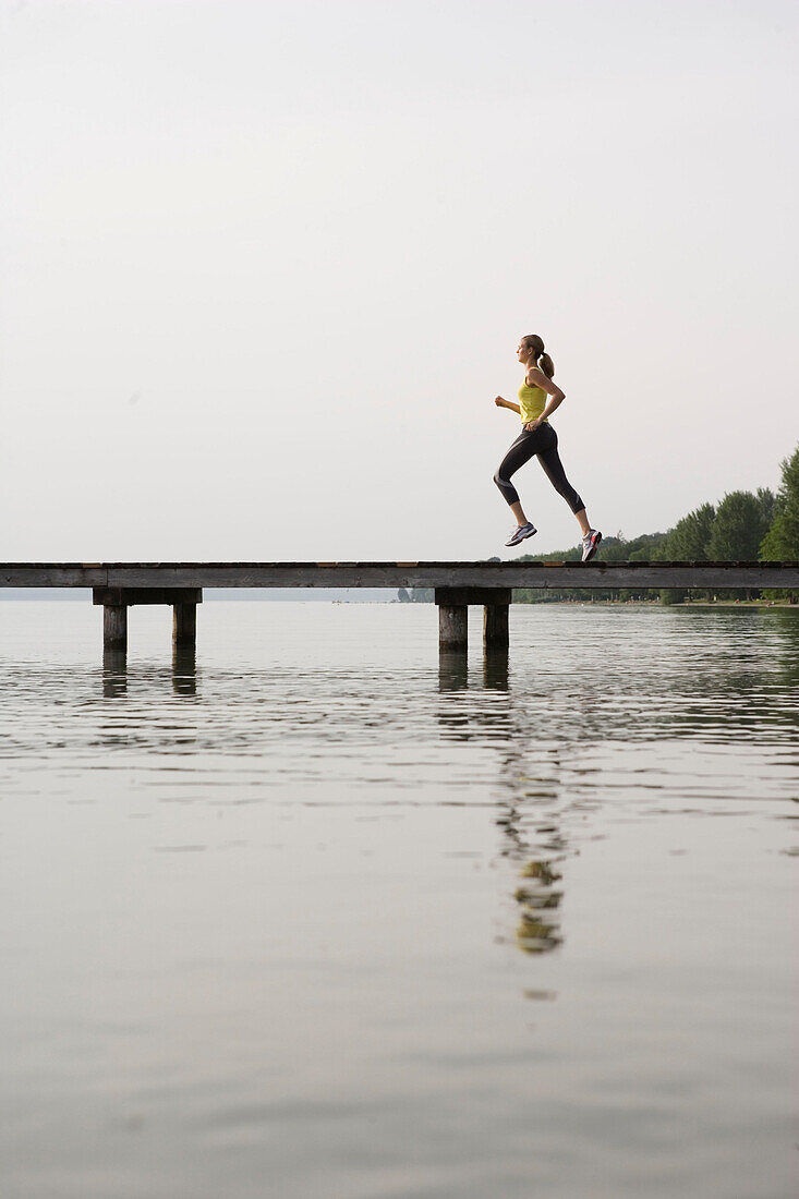 Young woman jogging on jetty