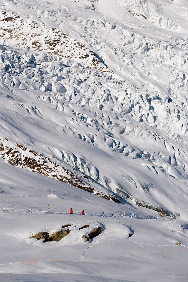 Two people walking on slope near glacier, Saas-Fee, Valais, Switzerland