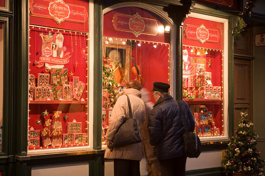 People standing in front of the christmassy decorated shop window of Reber, a shop, where you can buy Mozartkugeln, Old Market, Salzburg, Salzburg, Austria