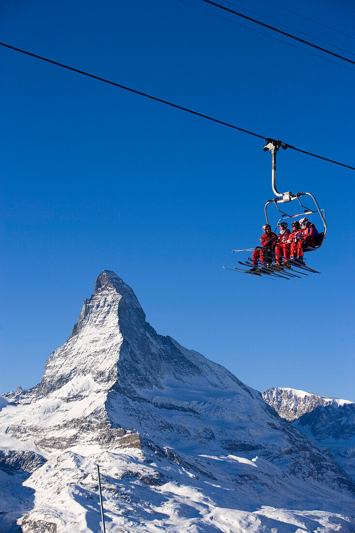 Skiers sitting on ski lift, Matterhorn in background, Zermatt, Valais, Switzerland
