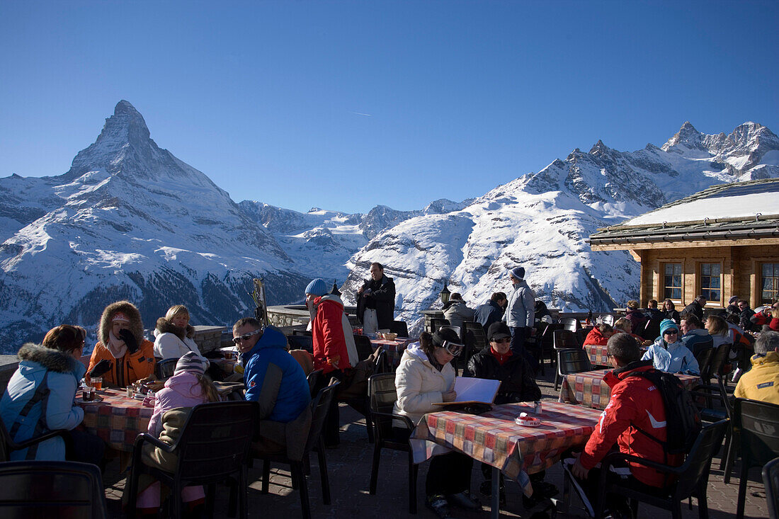 People sitting on the terrace of the Restaurant Blauherd with a view to the Matterhorn, Zermatt, Valais, Switzerland (2571 metres above sea level)