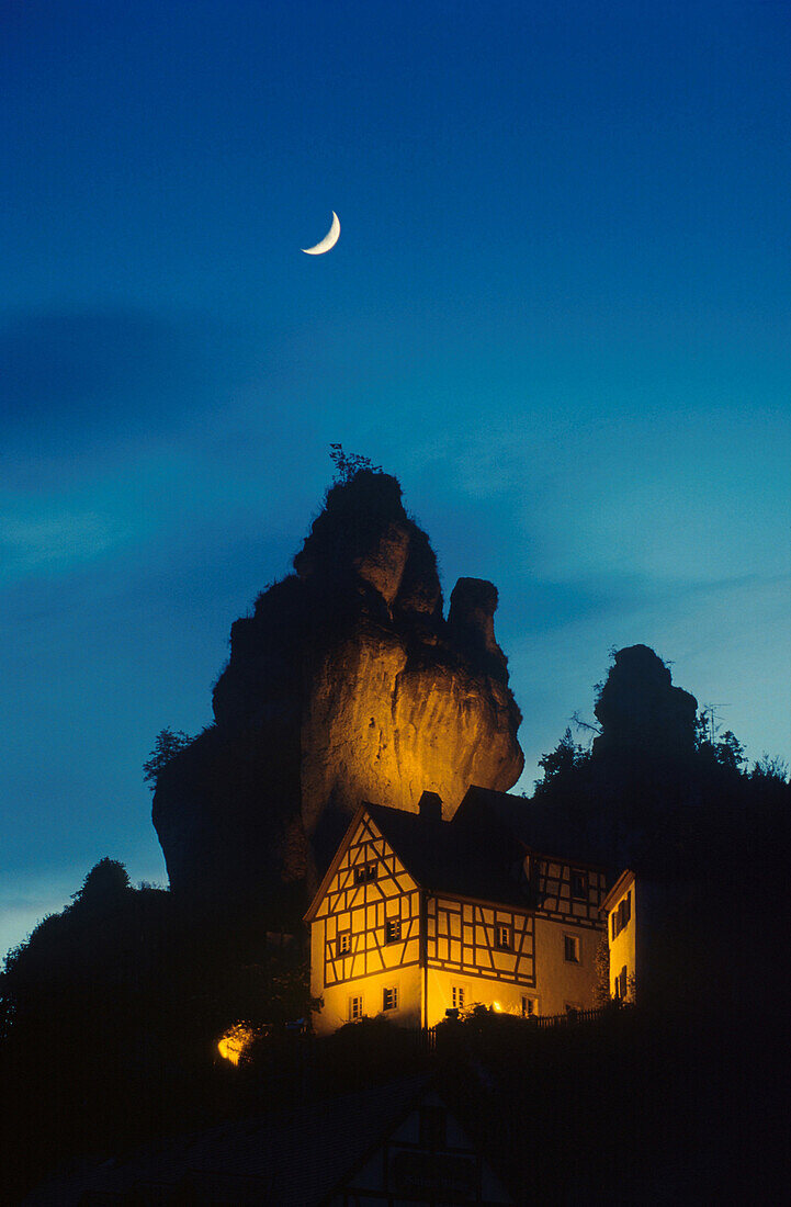 Illuminated house beneath big rock, Tuchersfeld, Franconia, Germany