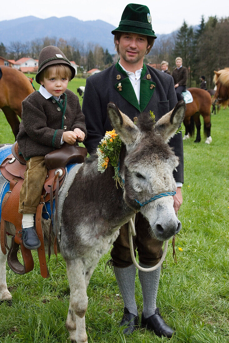 Father and son with donkey, traditional Georgiritt near Hub chapel, Penzberg, Upper Bavaria, Germany, MR