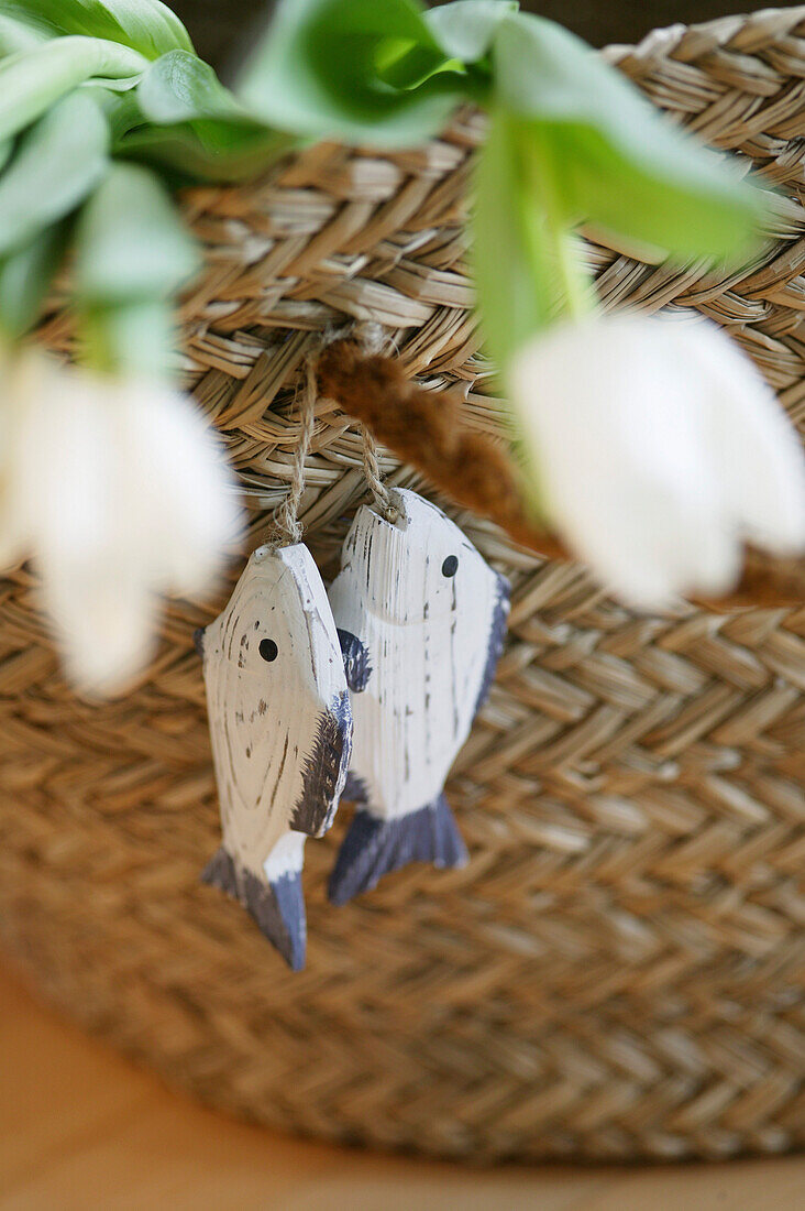 Geflochtener Korb mit zwei Holzfischen und Tulpen