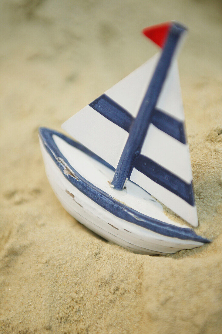 Wooden toy sailboat in the sand
