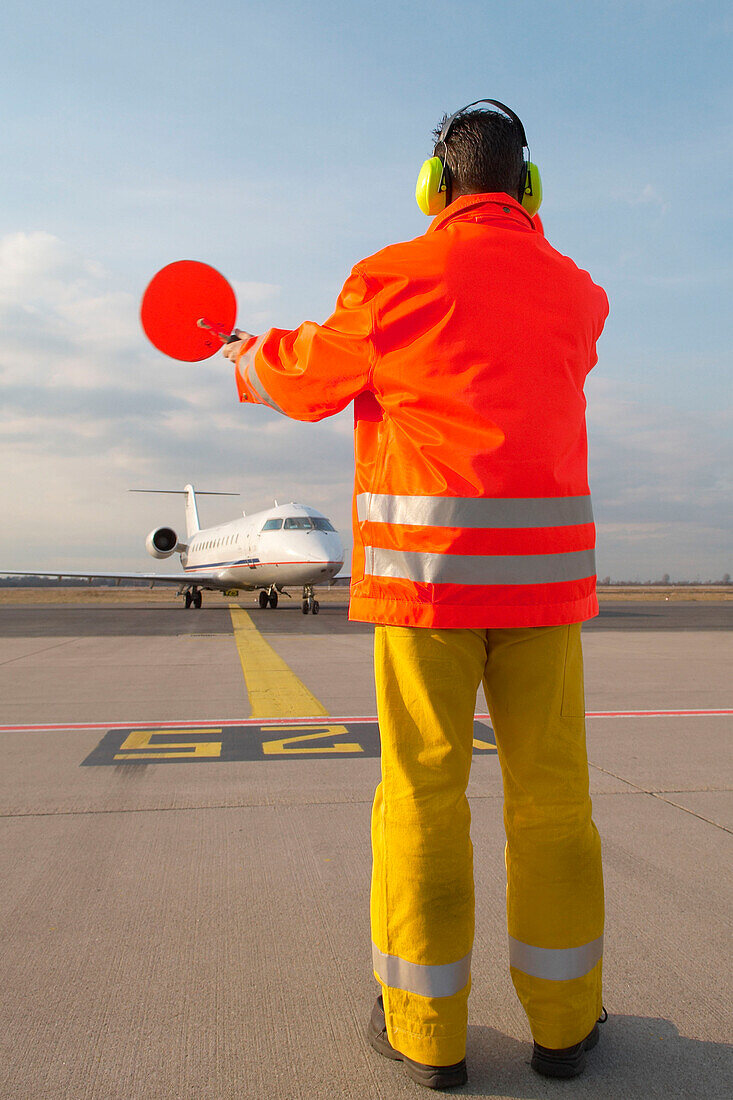 Airport ground crew signaling to aircraft, Airport Düsseldorf, North Rine-Westphalia, Germany