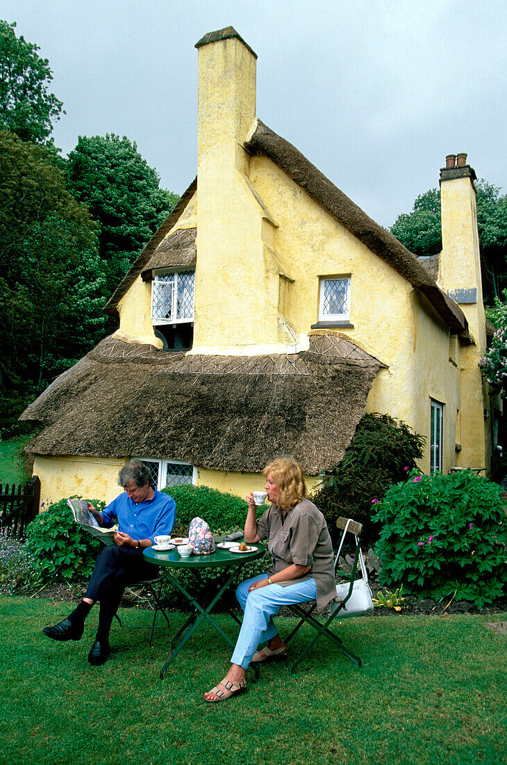 A couple sitting outside a cafe in a thatched house in Selworthy, Somerset