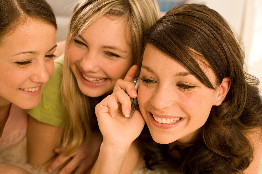 Weiblicher Teenager (14-16) telefoniert mit Handy, Freundinnen hören mit