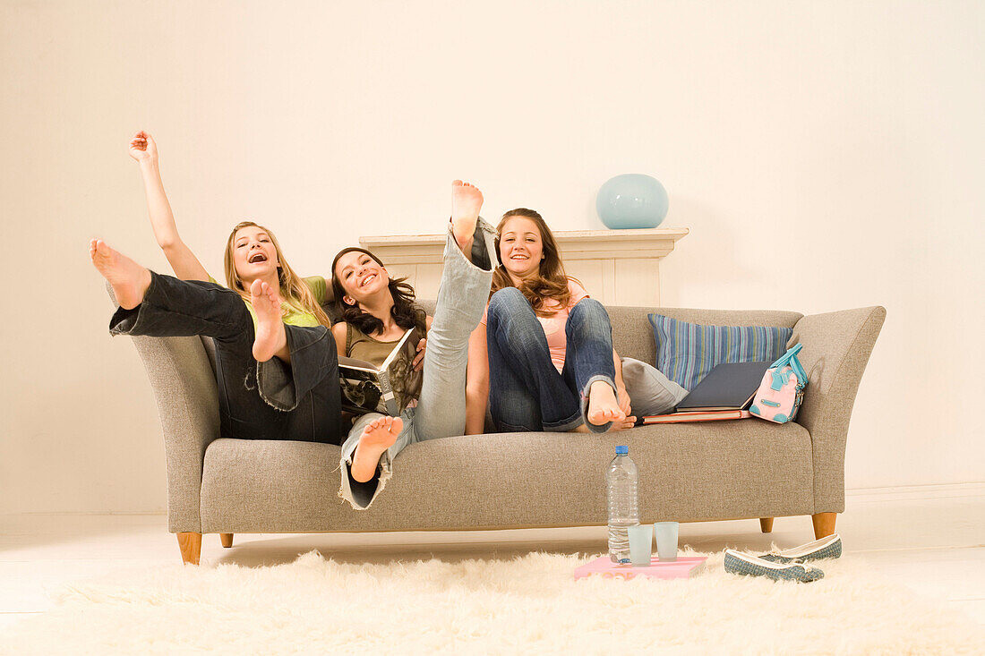 Weibliche Teenager (14-16) auf einem Sofa strecken die Beine hoch