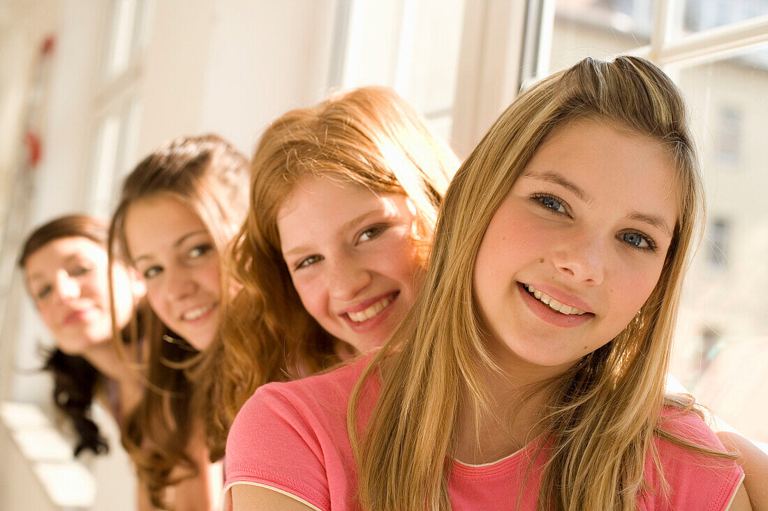 Weibliche Teenager (14-16) sitzen auf Fensterbank