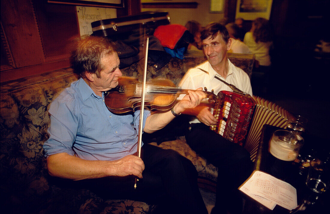Two men playing traditional music on violin and accordion in Gus O'Connor's Pub, Doolin, County Clare, Ireland