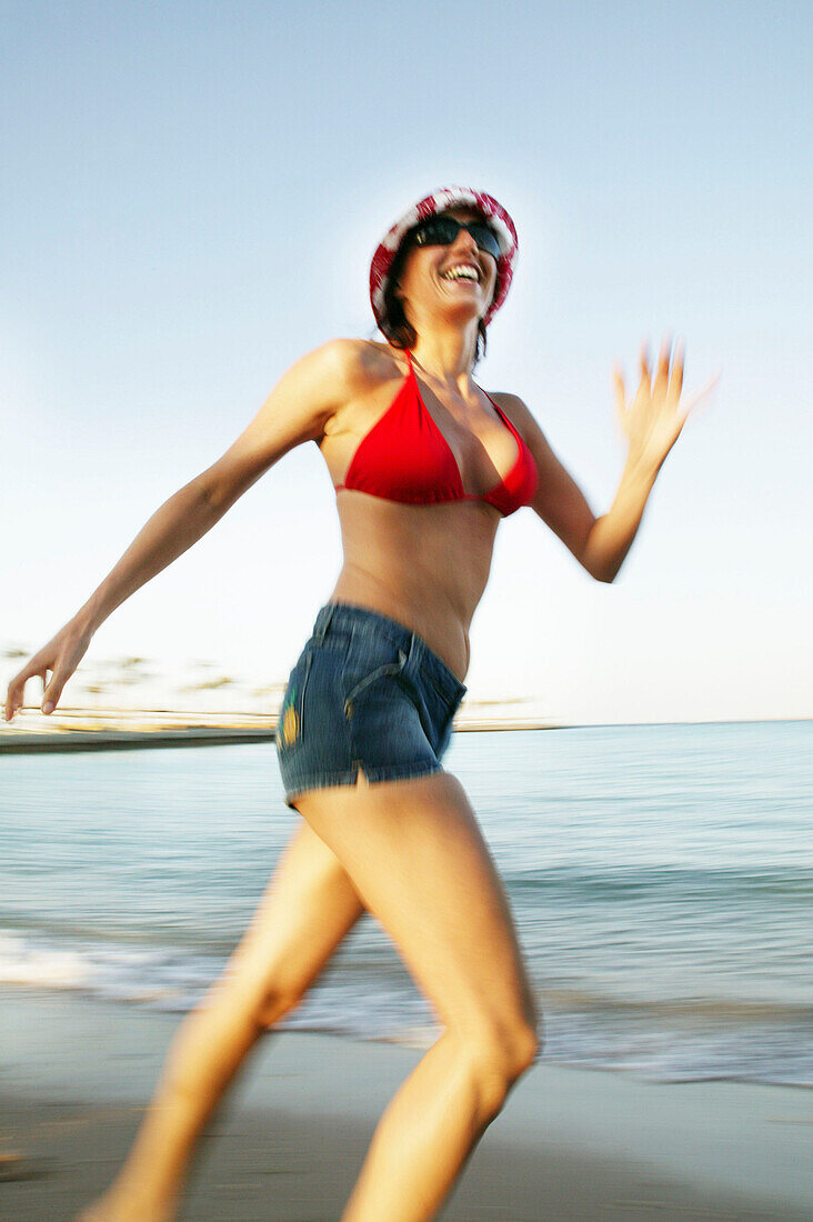 Junge Frau läuft am Strand entlang