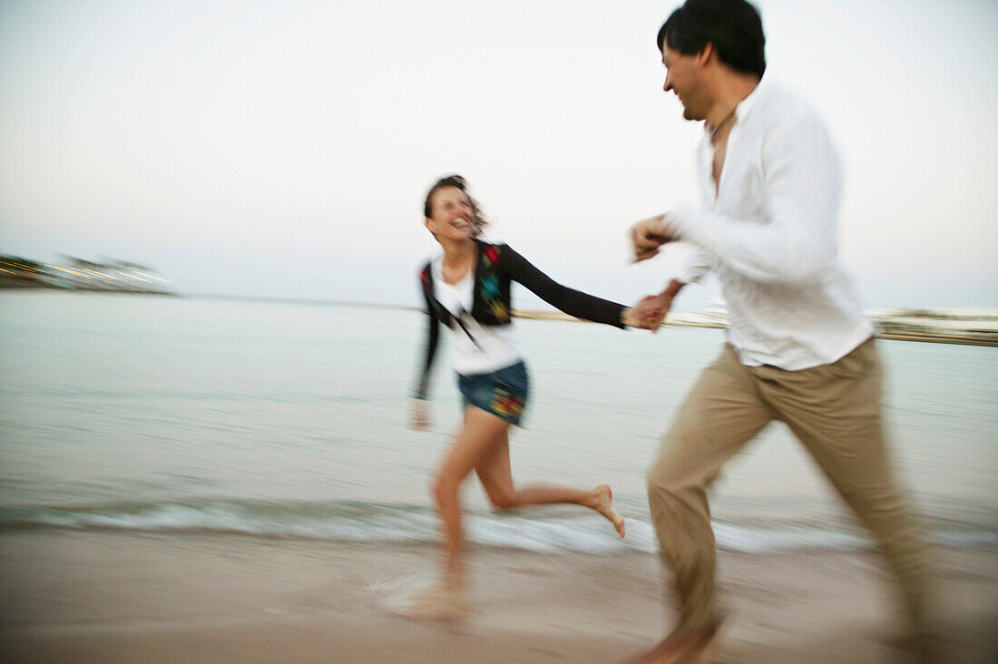 Couple in clothes running on the beach