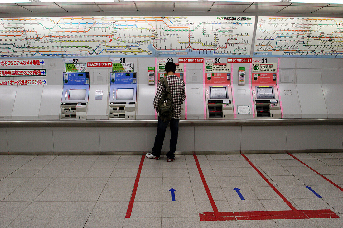 Young man in front of the ticket machine of a subway station, Tokyo, Japan