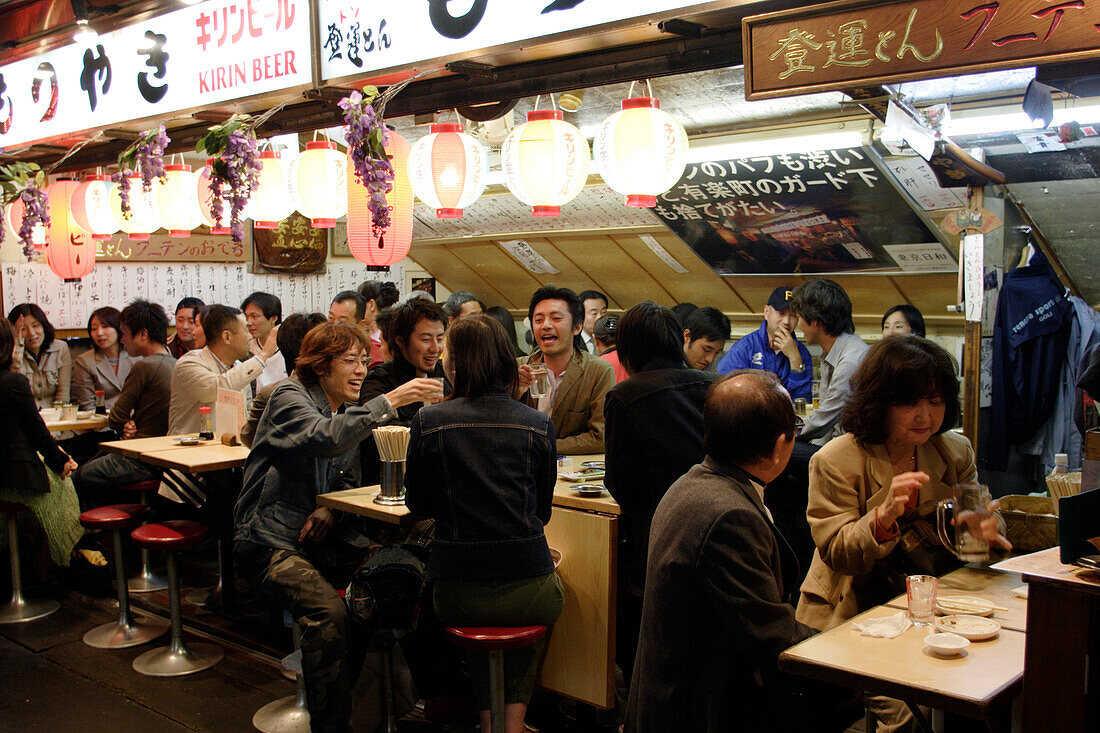 Menschen sitzen nachts in einem Schnellimbiss, Yurakucho Yakitori Alley, Ginza, Tokio, Japan