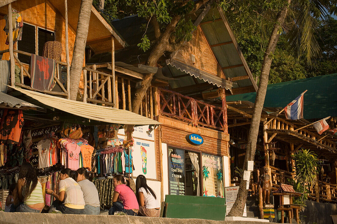 Girls sitting in front of a clothes shop at boardwalk, Ko Phi Phi Don, Ko Phi Phi Island, Krabi, Thailand, after the tsunami