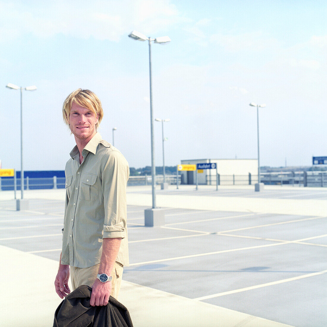 Man on parking place holding a jacket in his hand, Germany