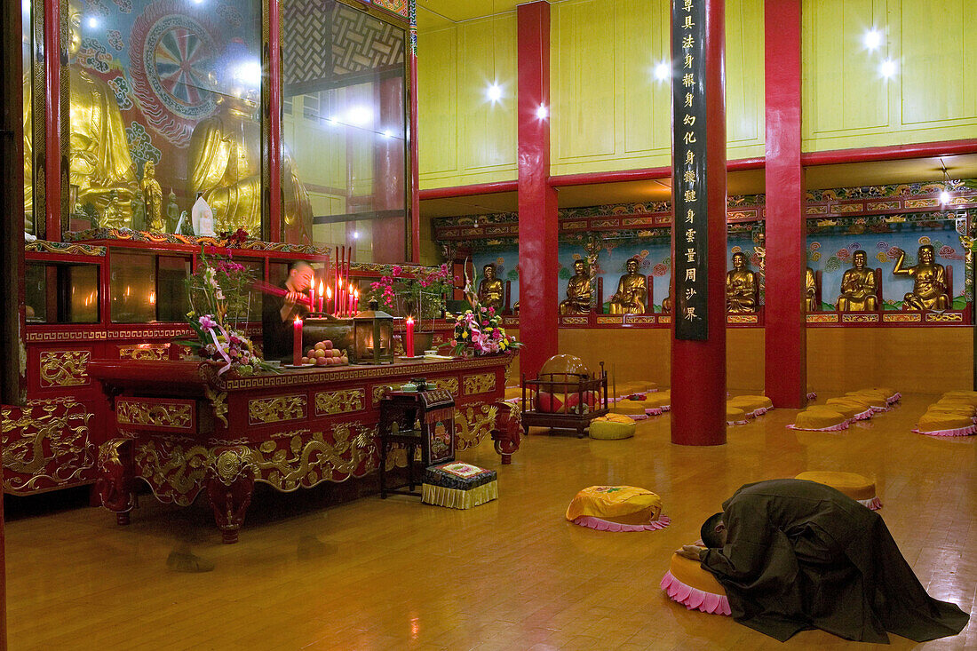 Praying monk at main hall of the Wannian monastery, Emei Shan, Sichuan province, China, Asia
