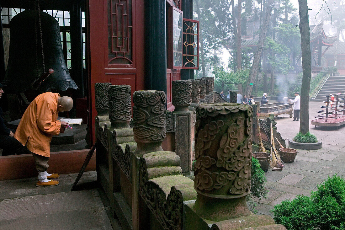 Old monk reading holy scripts in front of pavilion, Wannian monastery, Emei Shan, Sichuan province, China, Asia