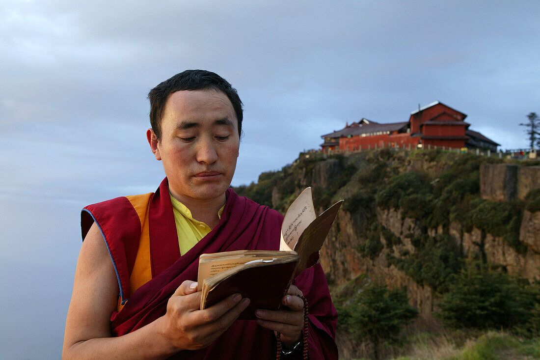 Tibetischer Mönch liest bei Sonnenaufgang heilige Schriften, Emei Shan Gebirge, Provinz Sichuan, China, Asien