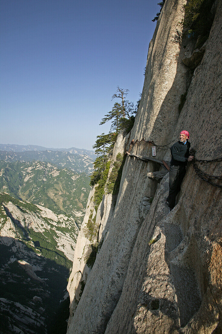 Himmelsleiter, Südgipfel, Hua Shan,Leitern und Stege aus Bohlen und Eisenstangen führen durch eine Steilwand zu einer ehemaligen Einsiedlerhöhle, hier wagemutig der Autor Uli Franz, taoistischer Berg, Huashan, Provinz Shaanxi, China, Asien