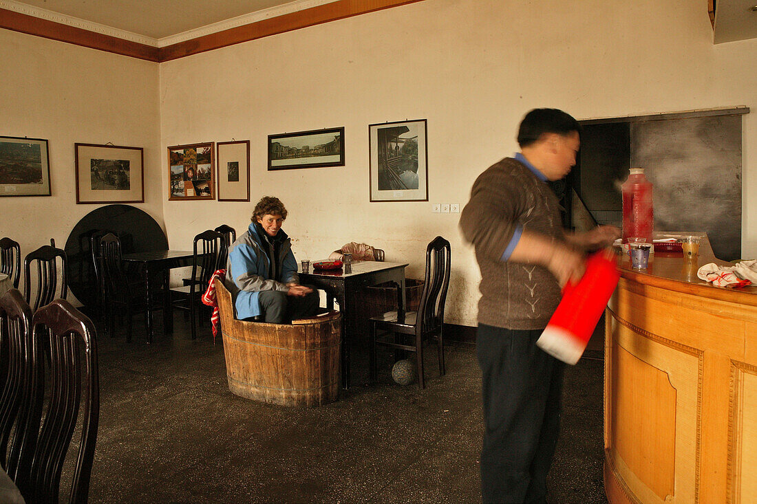 tourist sitting in a Huo Tong meaning fire barrel, to keep warm, heated from underneath, Hongcun, ancient village, living museum, China, Asia, World Heritage Site, UNESCO