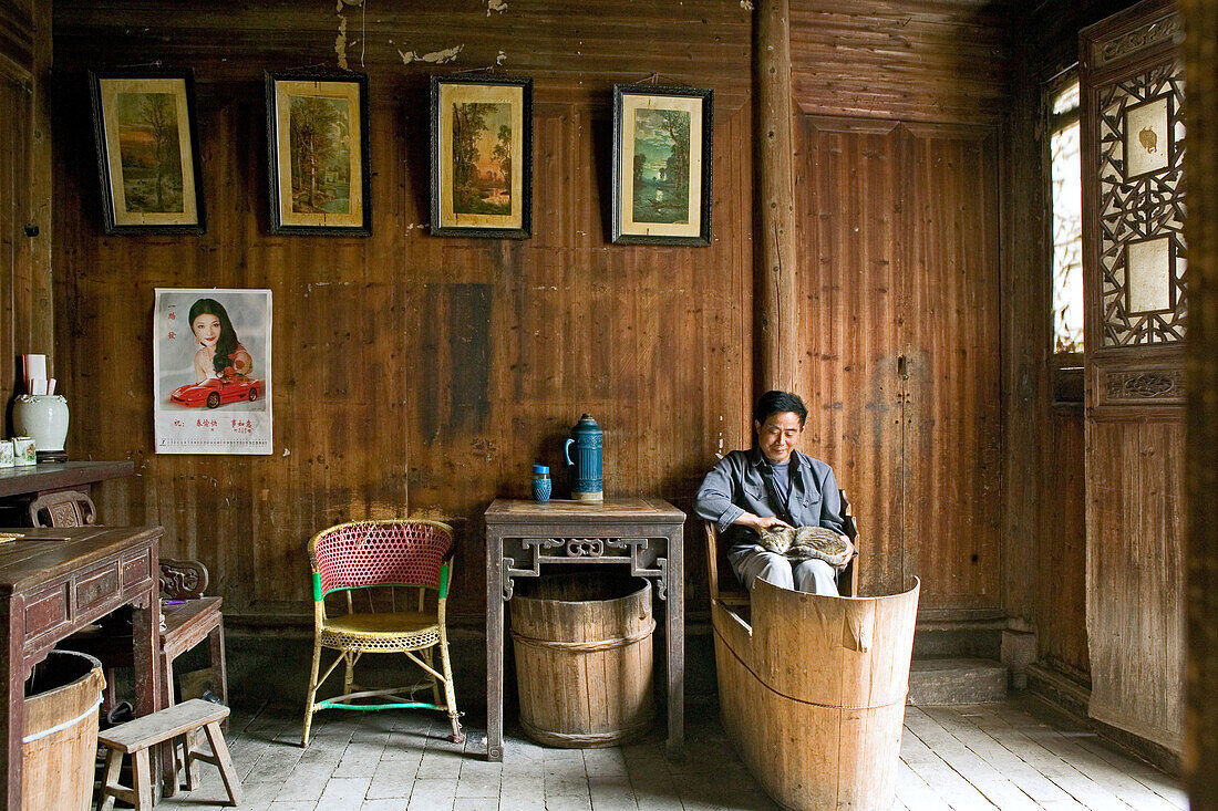 Mann mit Katze sitzt auf einem Fusswärmer Huo Tong, Hongcun, Huang Shan, China, Asien