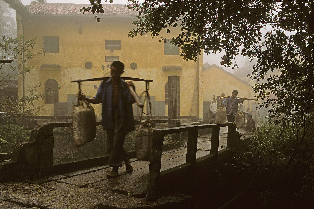 Träger mit Baumaterial vor dem Tianchi Kloster im Dorf Minyuan, Jiuhuashan, Provinz Anhui, China, Asien