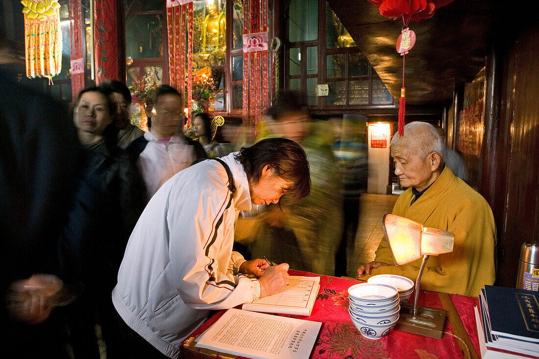 A monk and pilgrims at Longevity temple, Jiuhua Shan, Anhui province, China, Asia