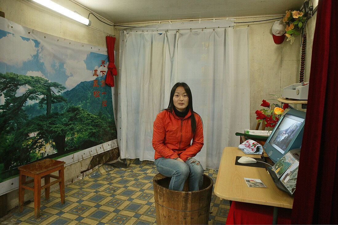 Young woman sitting on a foot warmer Huo Tong at a photo studio, Jiuhua Shan, Anhui province, China, Asia
