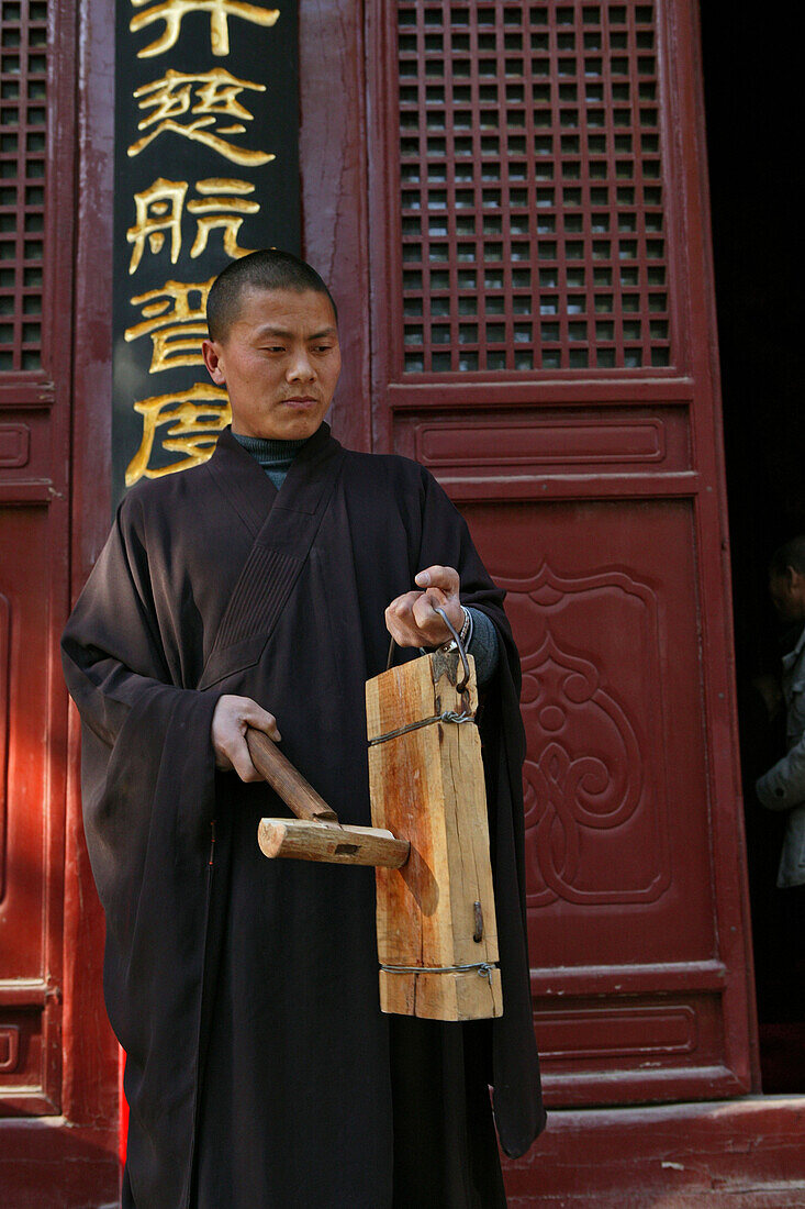 Buddhist Shaolin monk striking a wooden gong, Call for prayer, Shaolin Monastery, known for Shaolin boxing, Taoist Buddhist mountain, Song Shan, Henan province, China