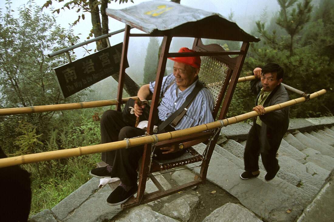 Träger tragen Touristen in Sänfte, Weg zum Nanya Palace, unterhalb Gipfel des Wudang Shan, daoistischer Berg in der Provinz Hubei, Gipfel 1613 Meter, Geburtsort des Taichi, China, Asien, UNESCO Weltkulturerbe