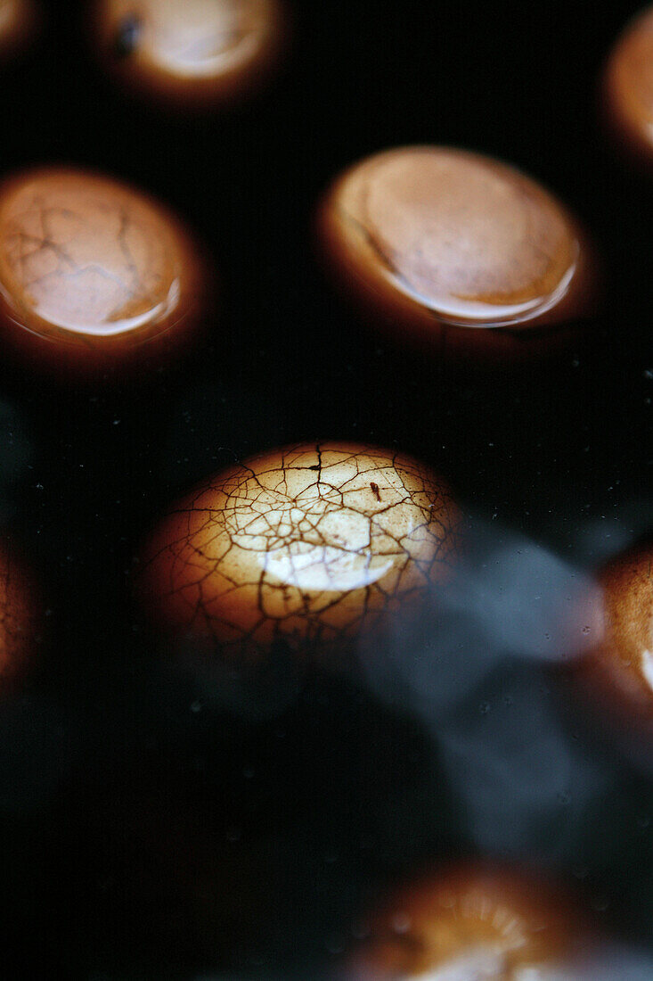 Close up of tea eggs, hard boiled eggs in black tea, soy sauce and spices, typical snack, chopsticks, China