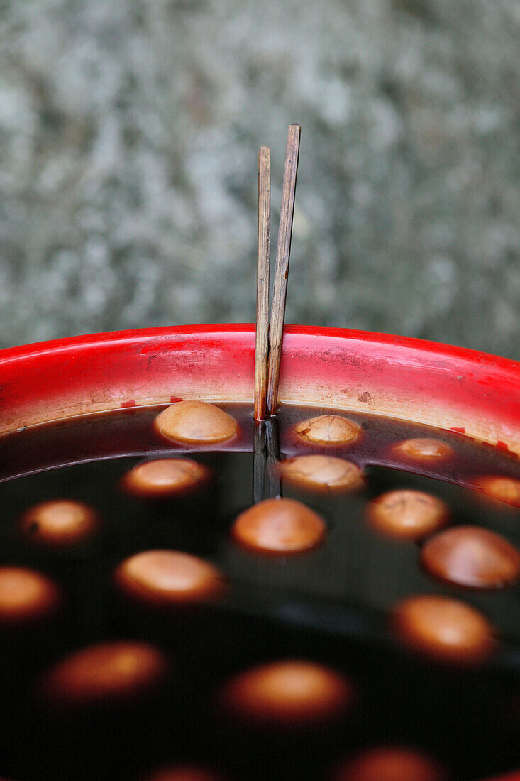 Tea eggs, hard boiled eggs in black tea, soy sauce and spices, typical snack, chopsticks, China