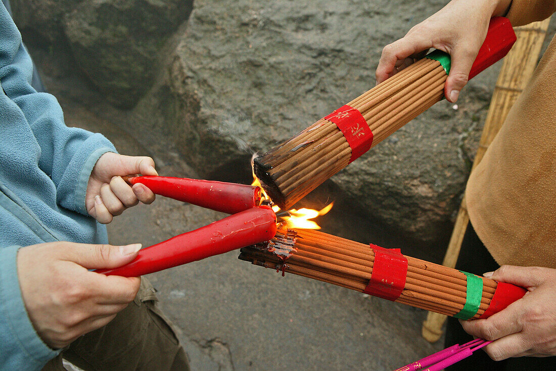 lighting bundles of incense sticks with red candles, pilgrims, China, Asien