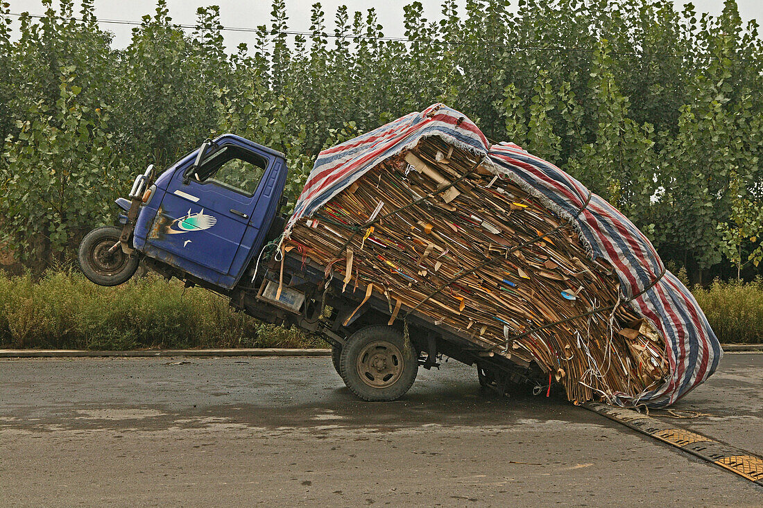 Overloaded three-wheeler on a deserted road, China, Asia