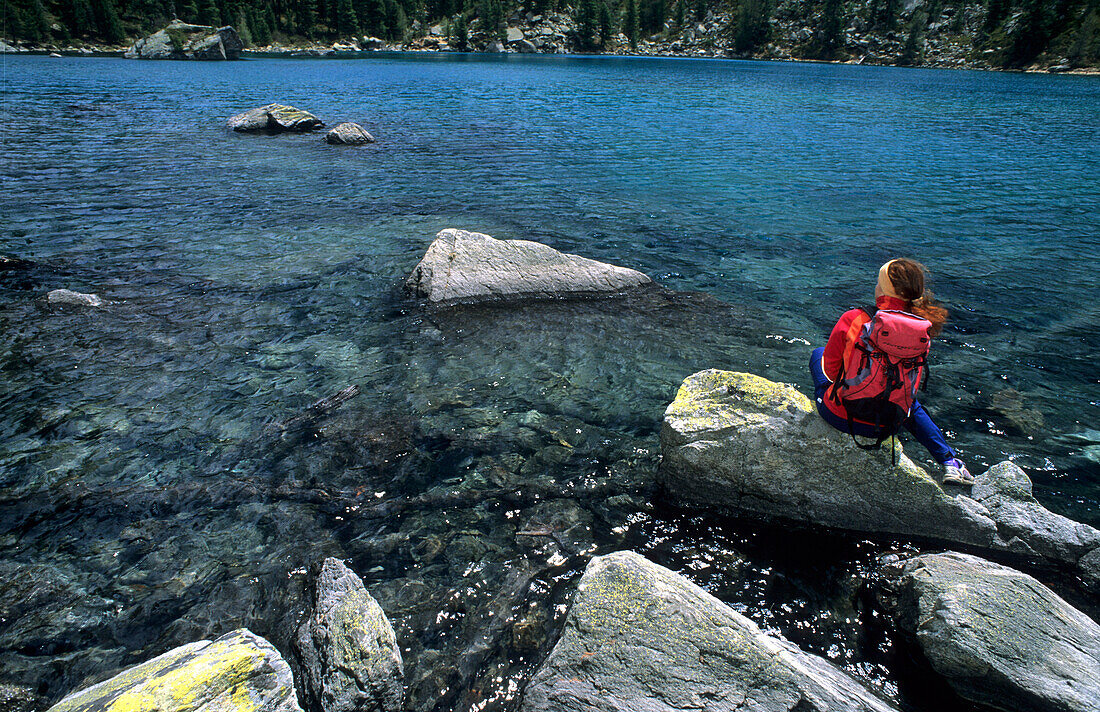 Saoseosee mit Wanderer auf Felsen sitzend, Livignoalpen, Graubünden, Schweiz